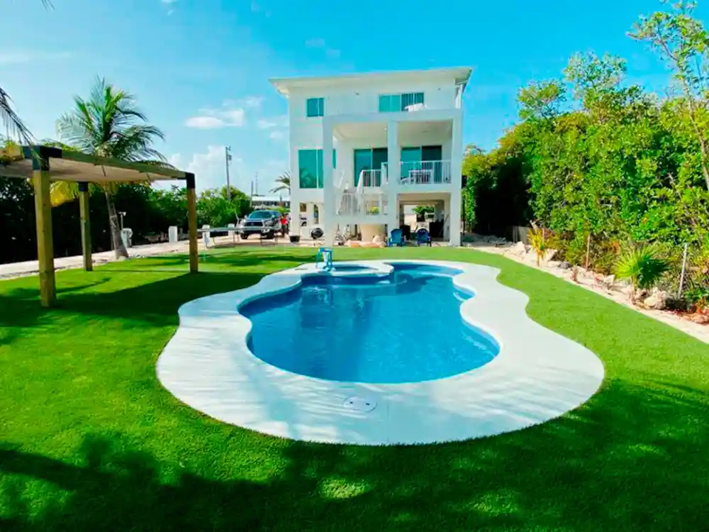 backyard pool with artificial grass around by top turf